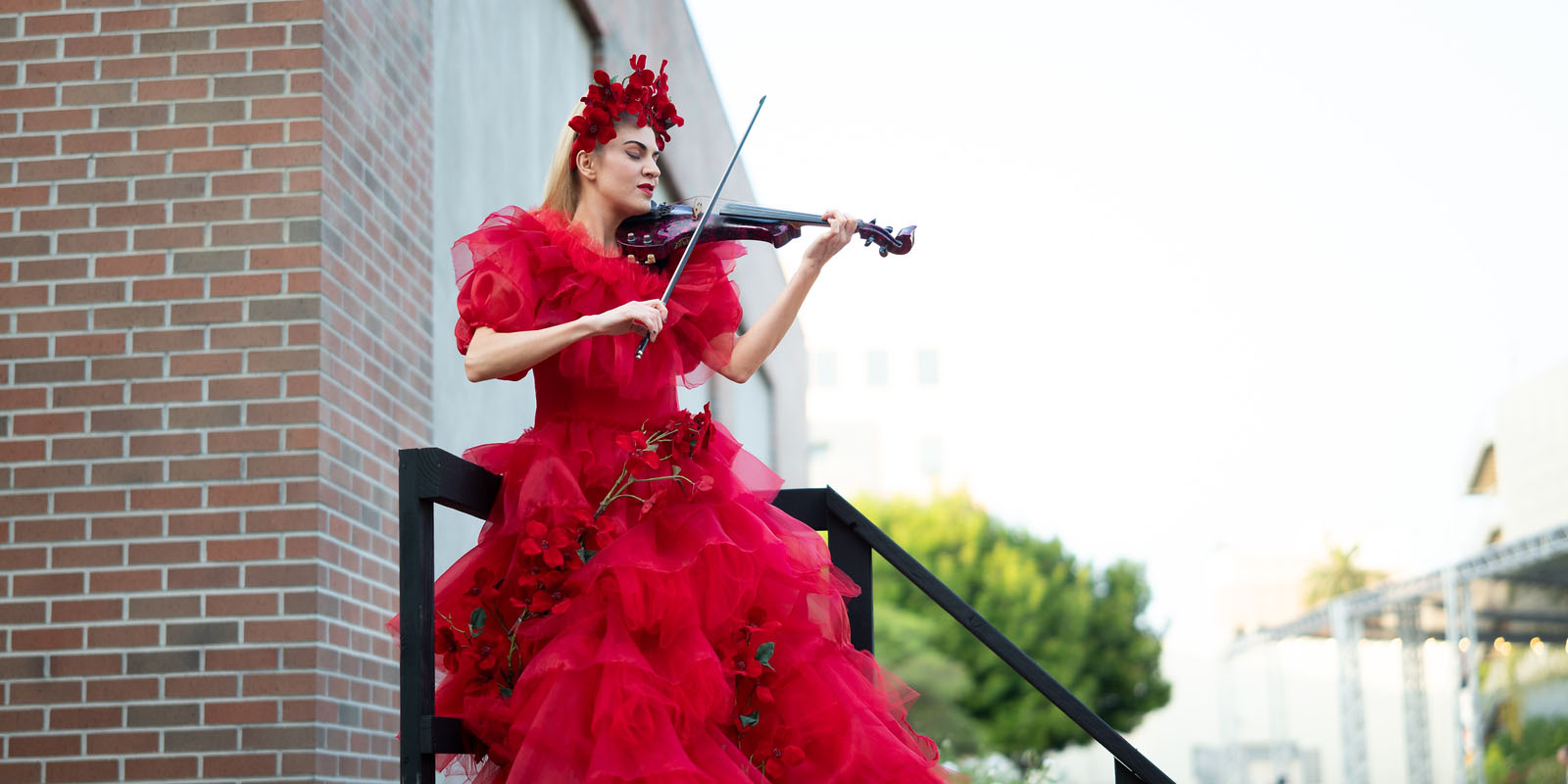 Violin player in a red dress on stairs.